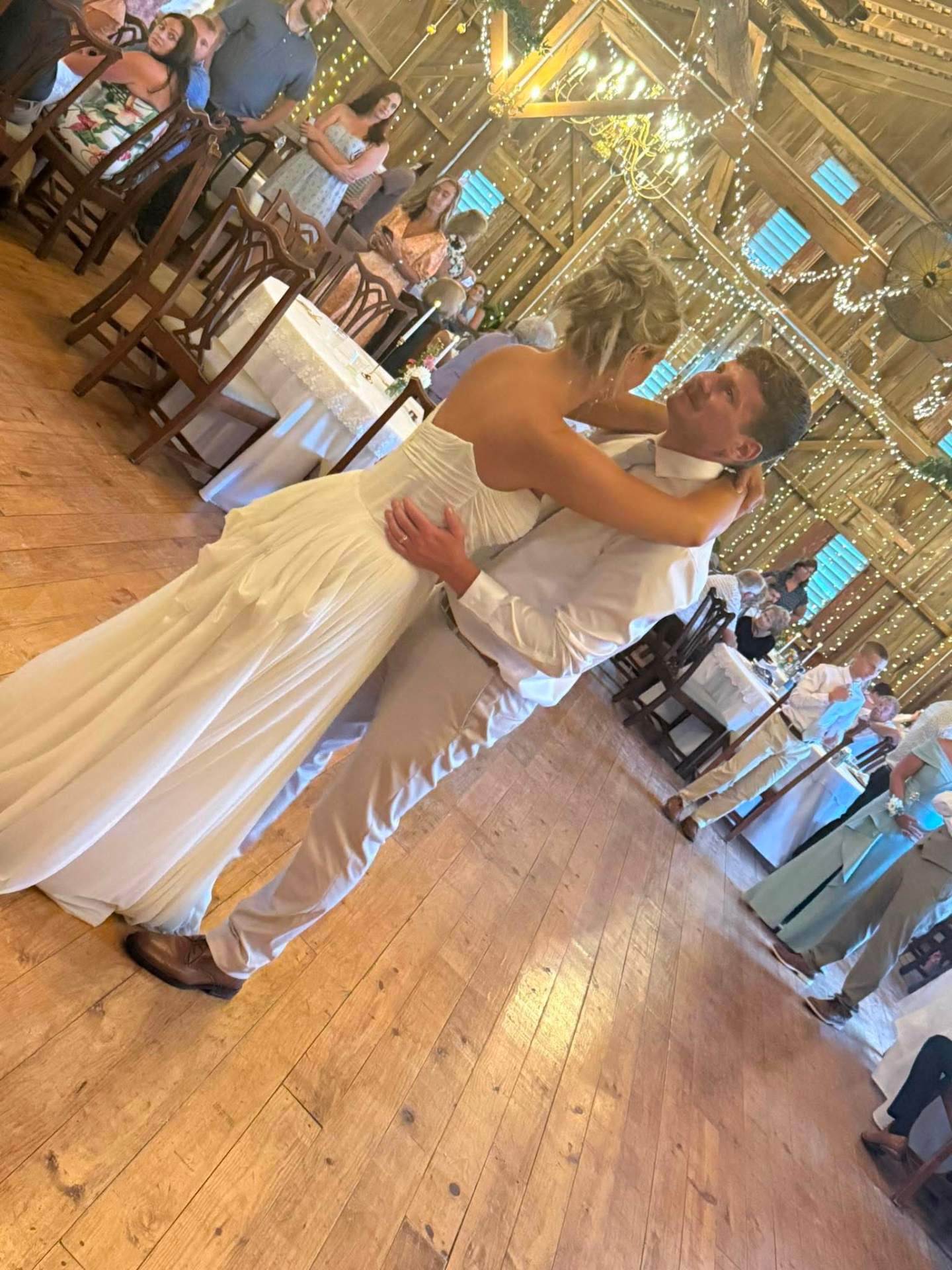 Bride and groom first dance in string-lit barn venue