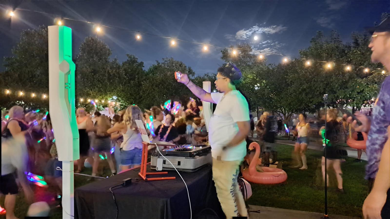 DJ Endy hyping a glowstick park crowd under string lights